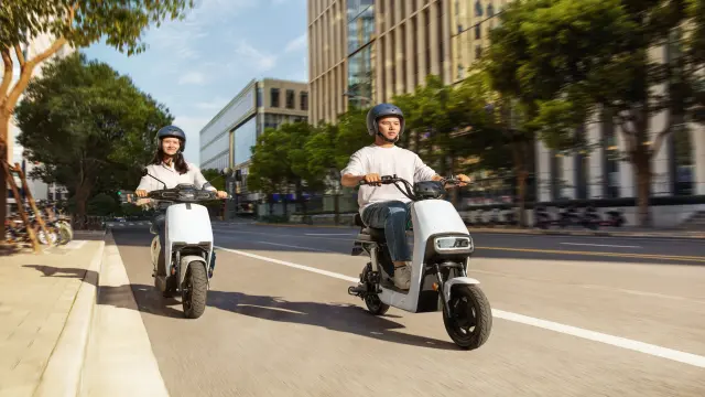 Couple riding electric scooters in a city.