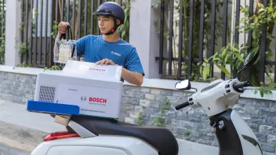 Male delivery driver closing a scooter mounted box.