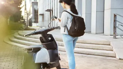 Woman unlocking a shared electric scooter with a mobile app.