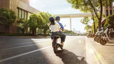 Woman riding at the back of a scooter with a professional driver.